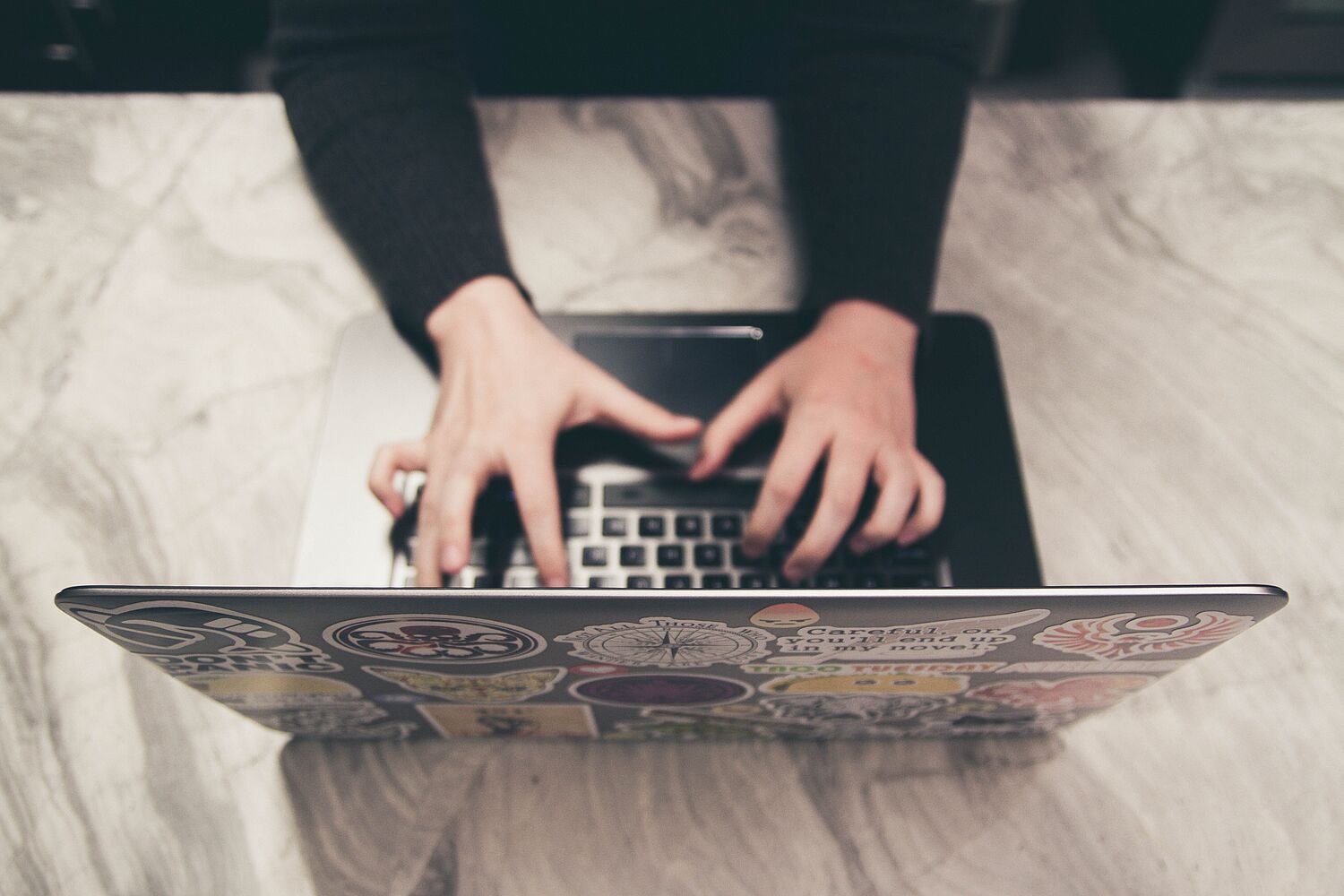 Hände schreiben etwas mit einem Laptop.