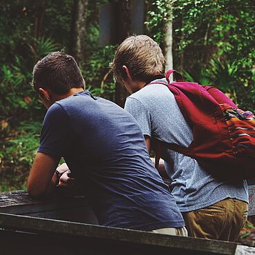 Zwei Jungen stehen in einem Wald.