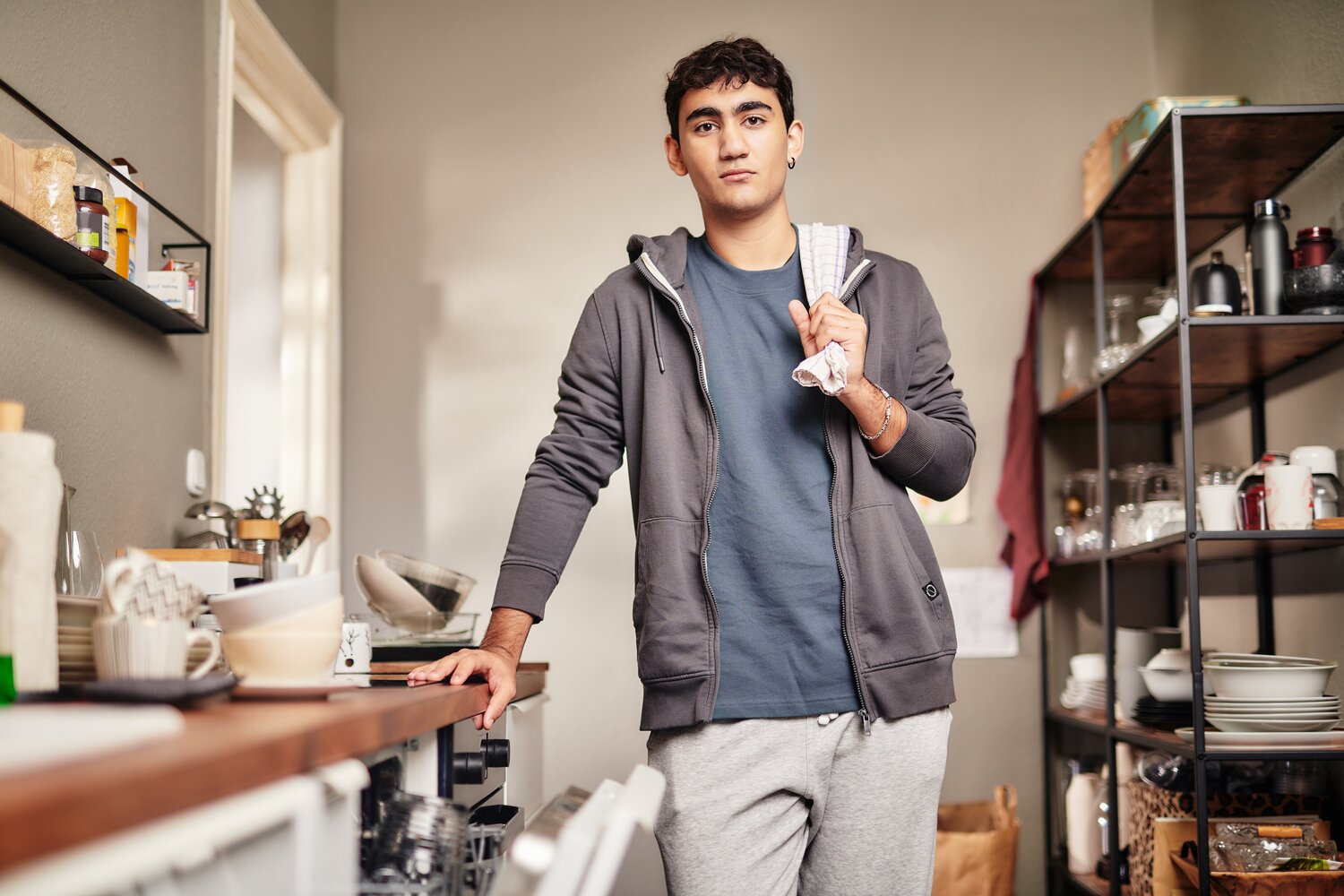 Ein Junge steht mit iner Hand angelehnt an einer Küchenzeile